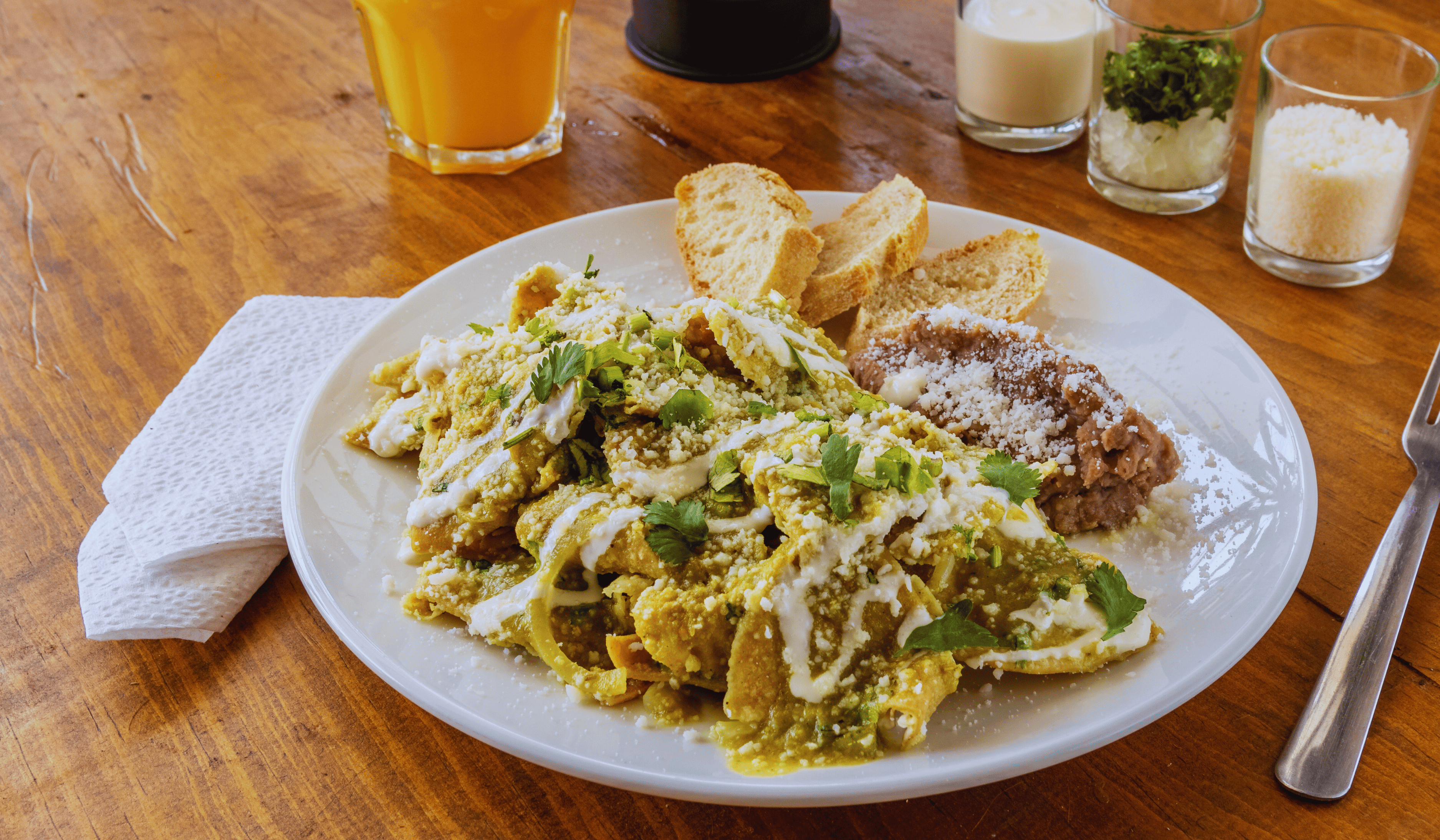 Mexican green chilaquiles with chicken and cheese on wooden background