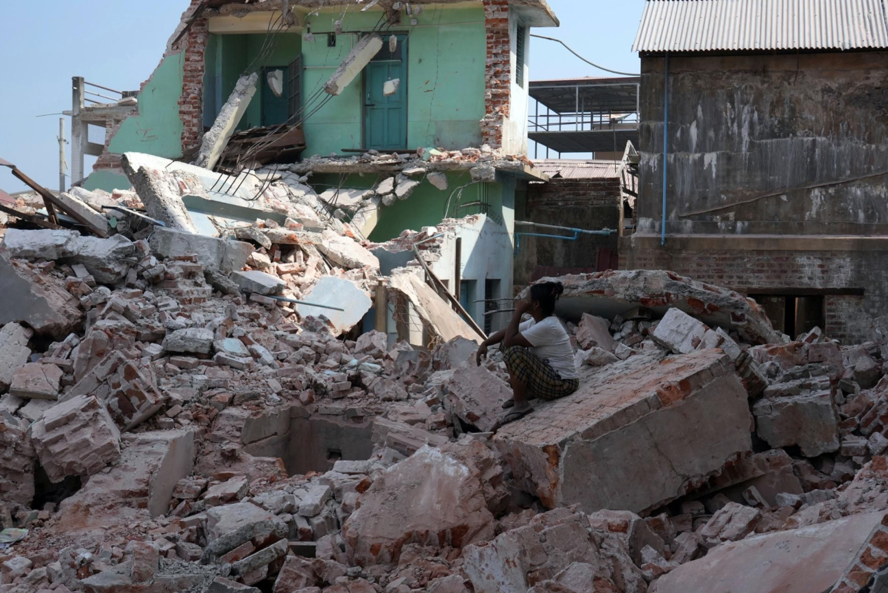 A volunteer sits atop the rubble of a collapsed building nearly one month after a powerful earthquake struck Naypyitaw, Myanmar, on April 28.