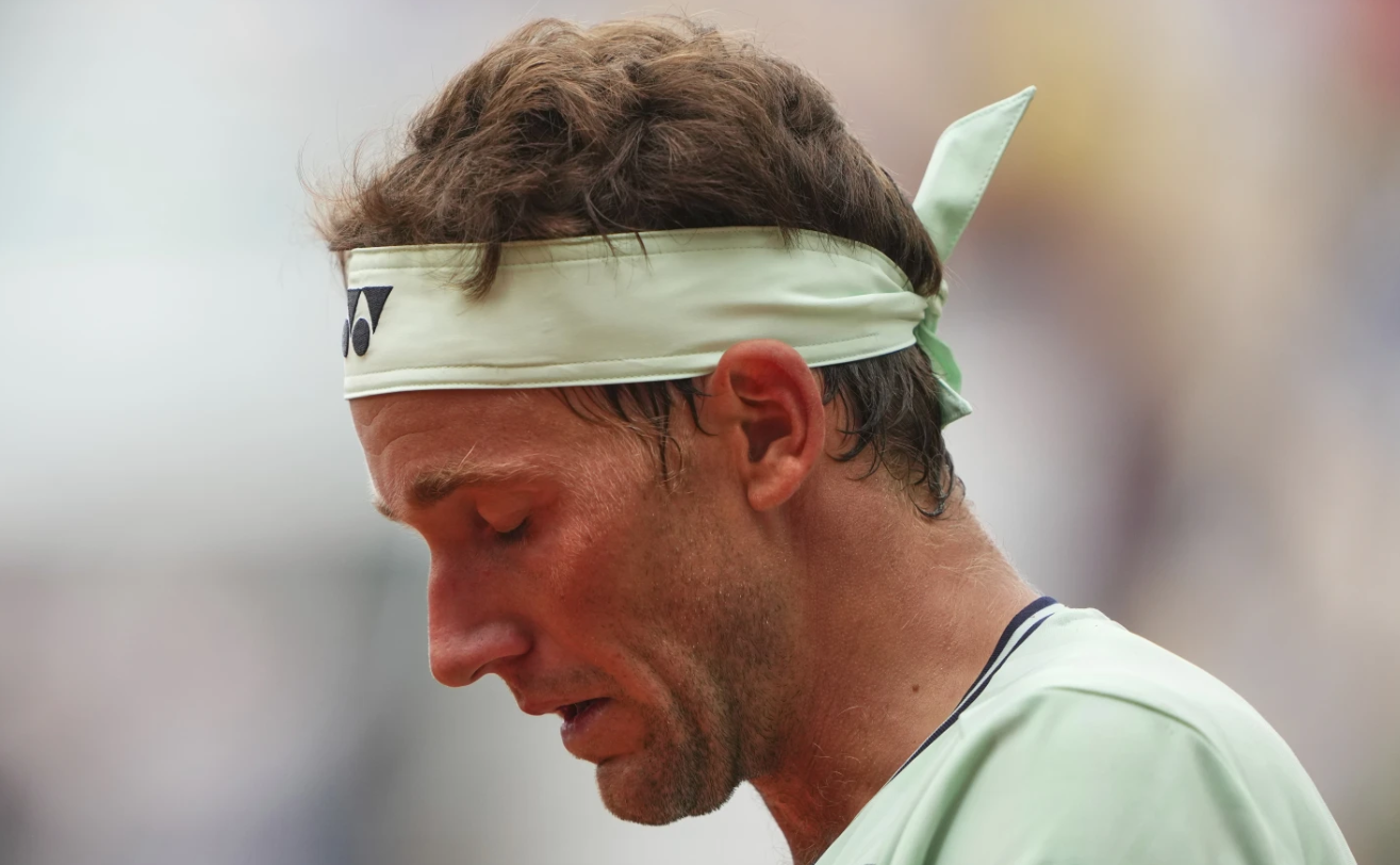 Casper Ruud looks down after battling through knee pain in his second-round loss to Nuno Borges at the 2025 French Open.