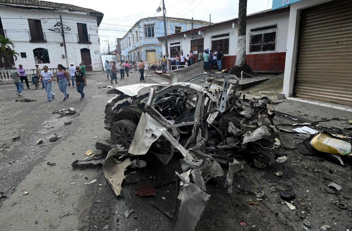 A burned-out car sits in the middle of a debris-strewn street after a powerful explosion in southwest Colombia on June 10, 2025. The blast, one of several that rocked the region, left behind scorched metal and shattered windows, as emergency crews and bystanders surveyed the damage.